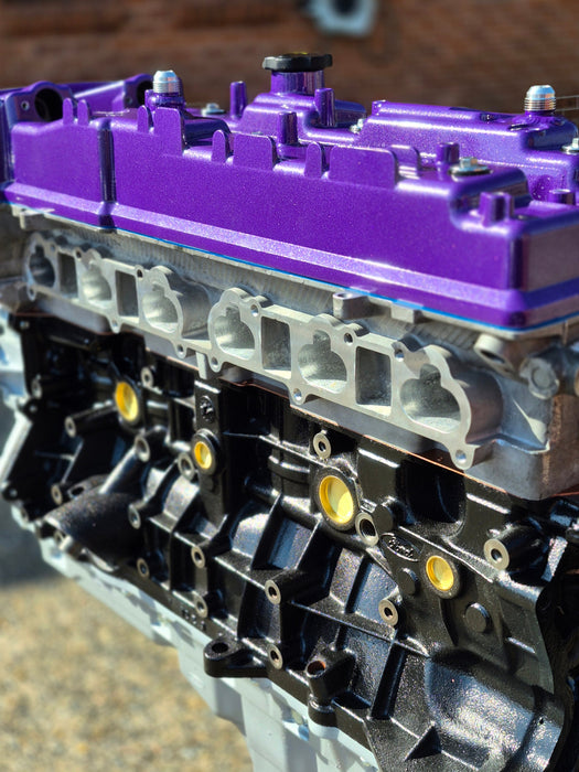 complete engine on display with purple rocker cover with brick background