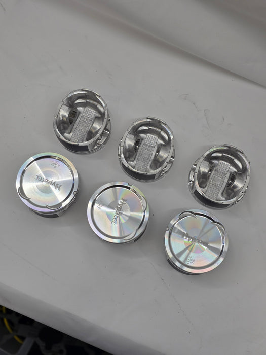 close up of top and underside of  cast engine piston heads on white background